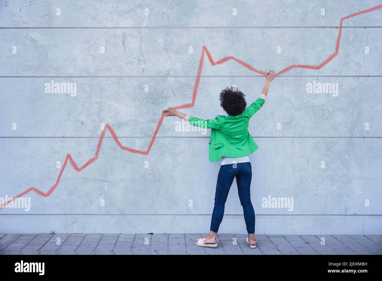 Junge Frau, die auf ein Diagramm zeigt, das auf die Wand gemalt ist Stockfoto
