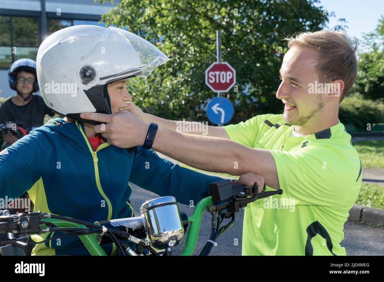 Trainer, der den Sicherheitshelm des Jungen auf dem Quadbike justiert Stockfoto