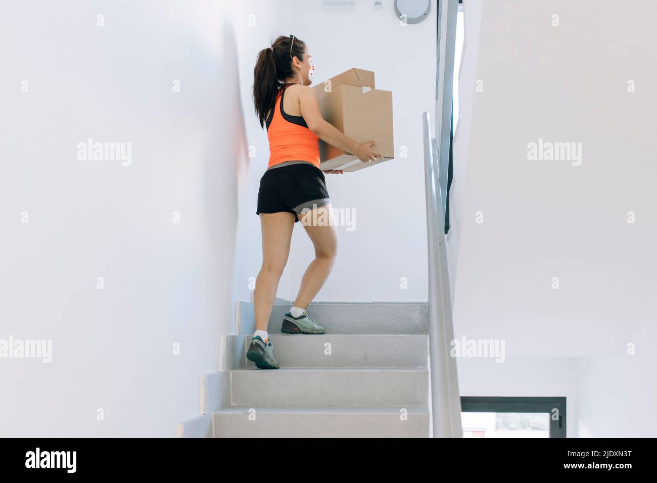 Frau mit Pappkartons, die sich auf Stufen hochbewegen Stockfoto