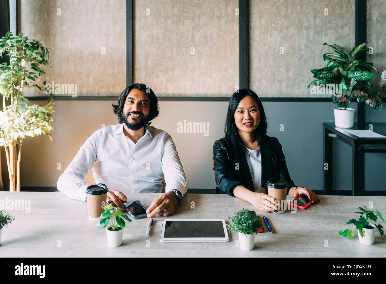 Multirassische Geschäftskollegen mit wiederverwendbaren Tassen am Schreibtisch Stockfoto
