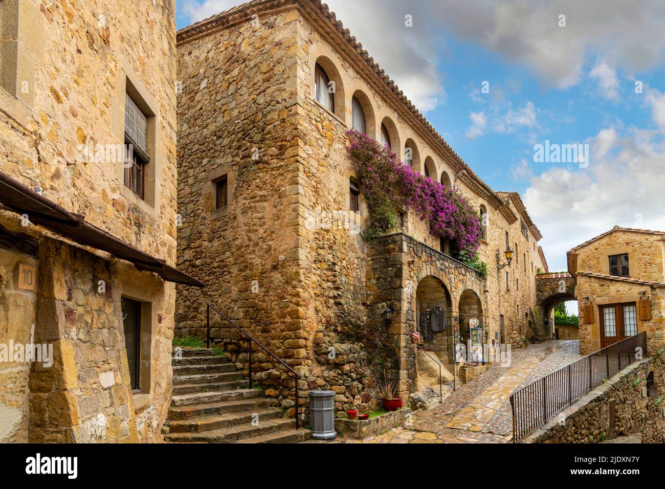 Ein kleines Geschäft mit violetten Bougainvillea-Büschen im mittelalterlichen ummauerten Dorf Pals Spanien an der Costa Brava. Stockfoto