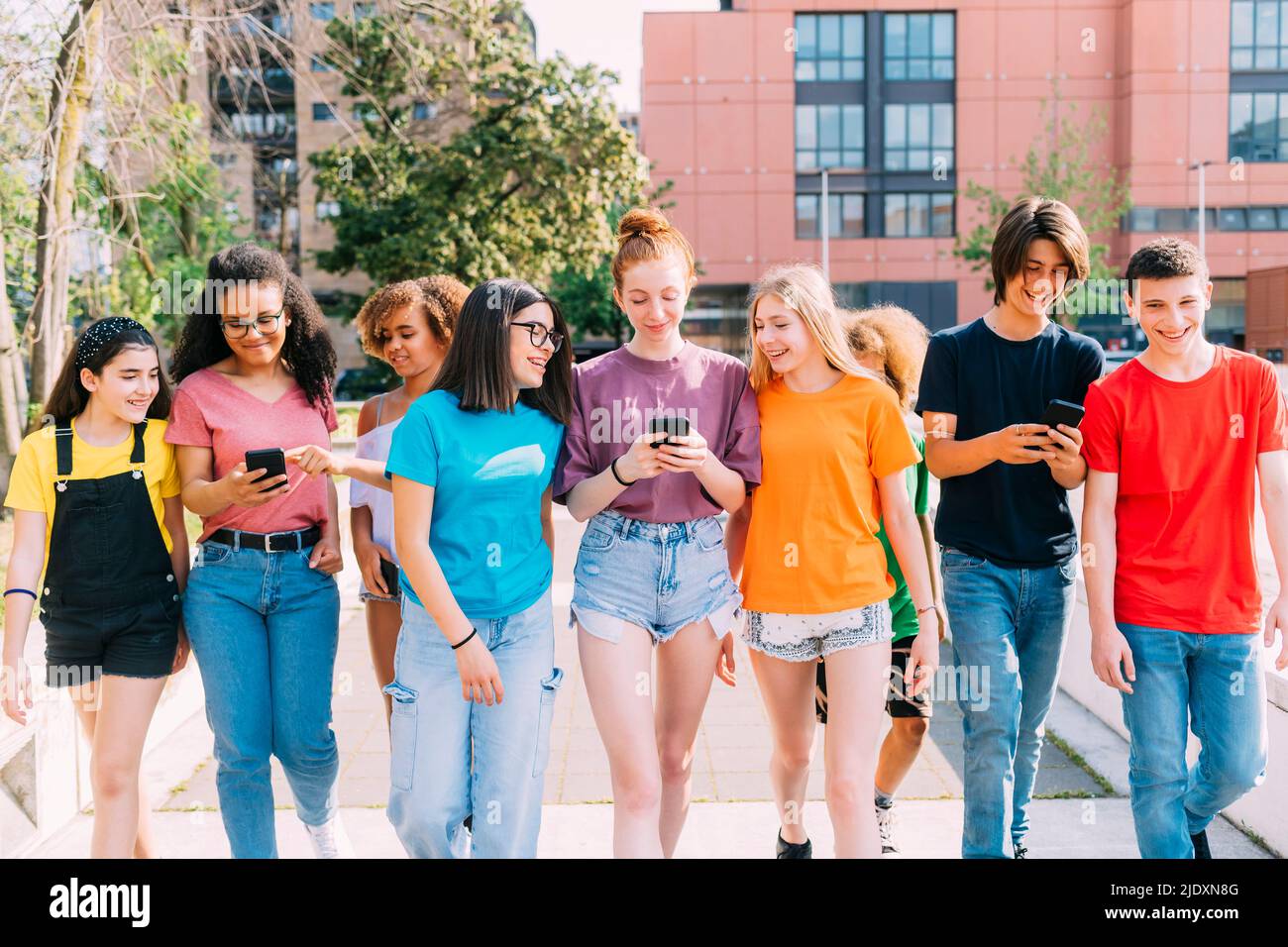 Lächelnde, multirassische Freunde, die Smartphone benutzen, um zusammen zu gehen Stockfoto