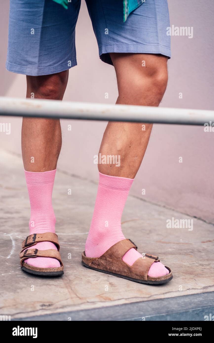 Beine eines Mannes in rosa Socken und Sandalen Stockfoto