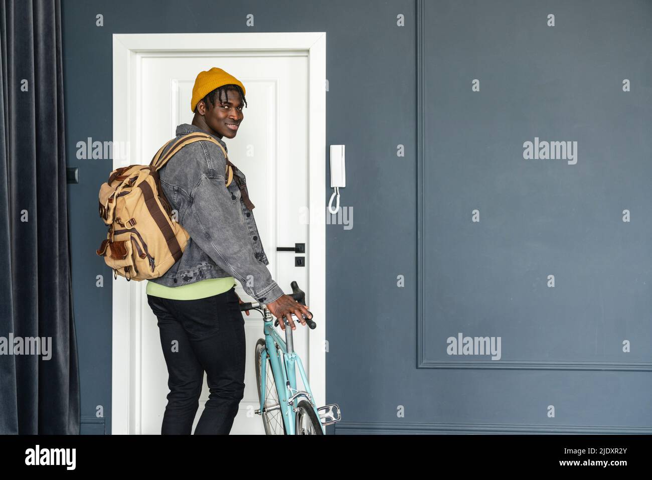 Lächelnder Student mit Fahrrad vor der Tür Stockfoto