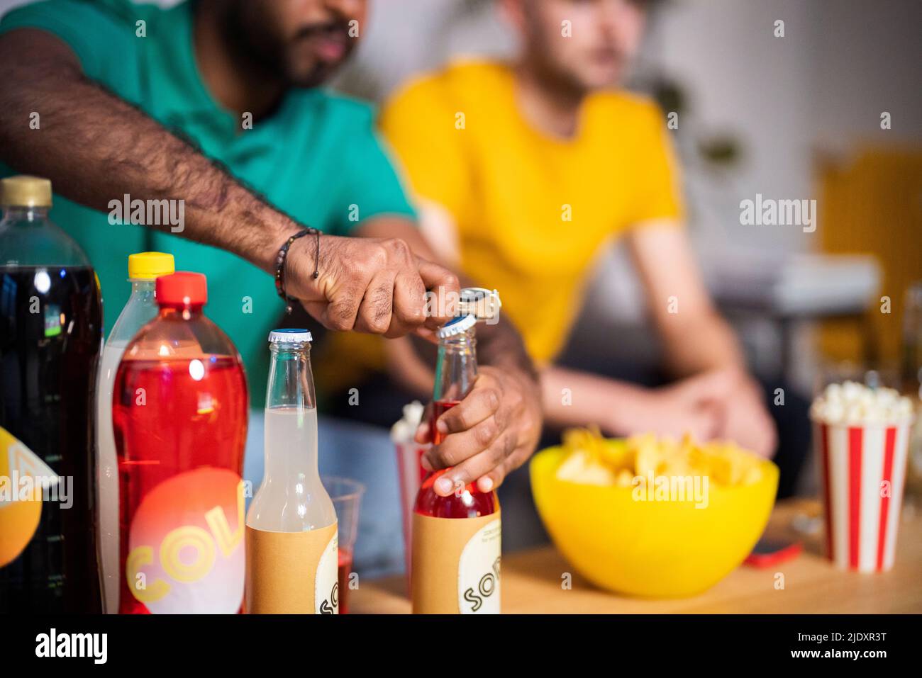 Hände eines jungen Mannes, der zu Hause eine Flasche Getränk öffnet Stockfoto