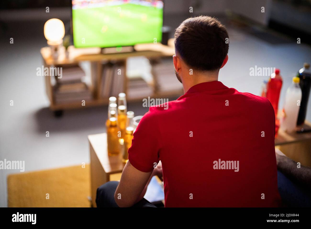 Junger Mann, der sich zu Hause ein Fußballspiel ansieht Stockfoto
