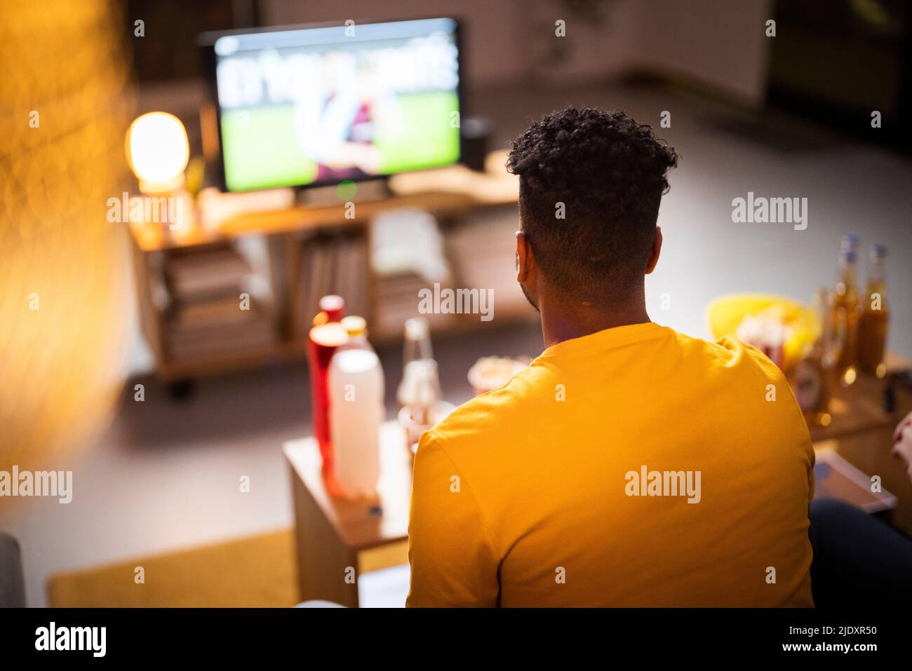 Junger Mann, der sich zu Hause ein Fußballspiel ansieht Stockfoto