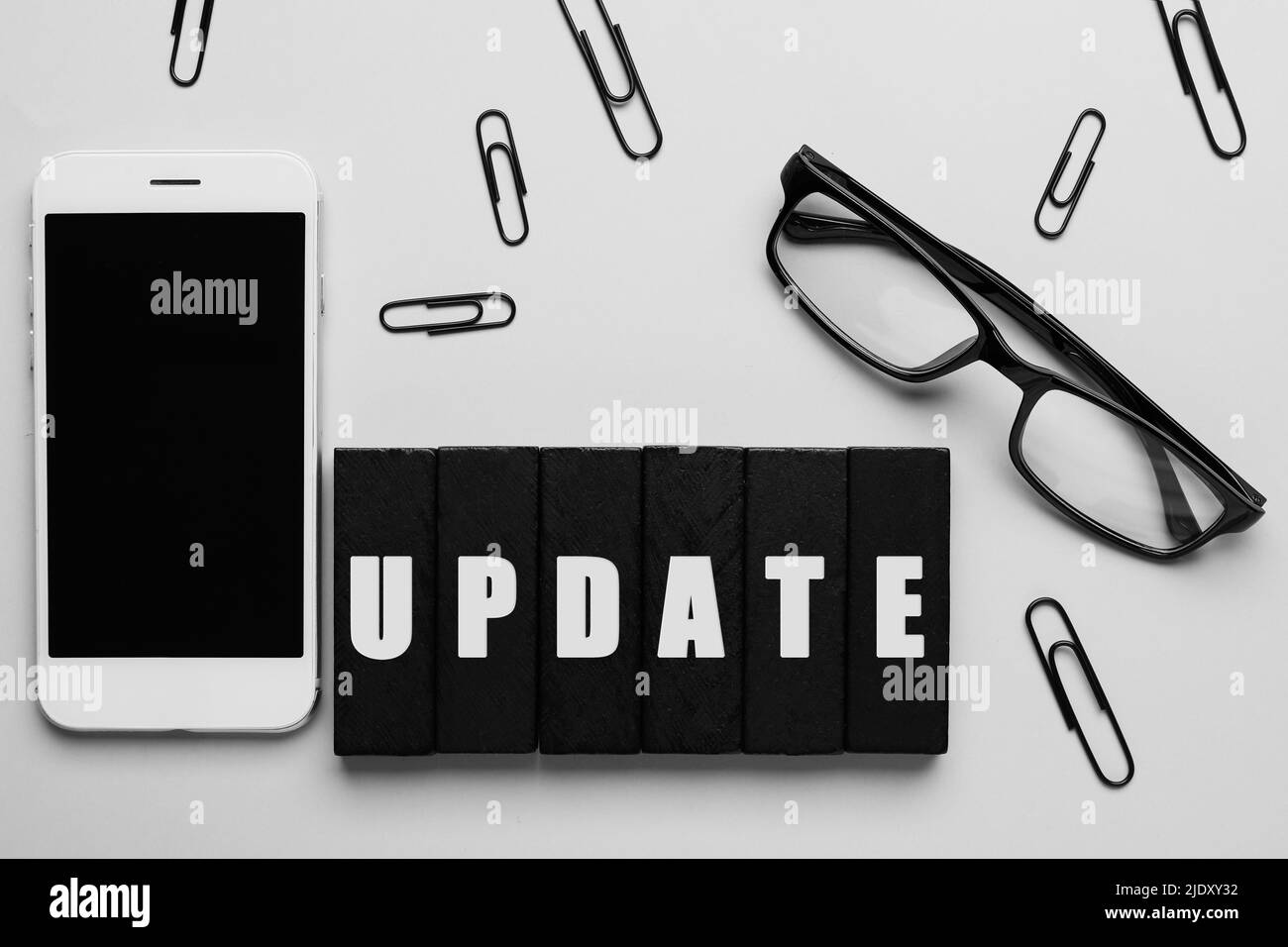 Word-UPDATE aus Blöcken, Smartphone, Brille und Büroklammern auf hellem Hintergrund Stockfoto