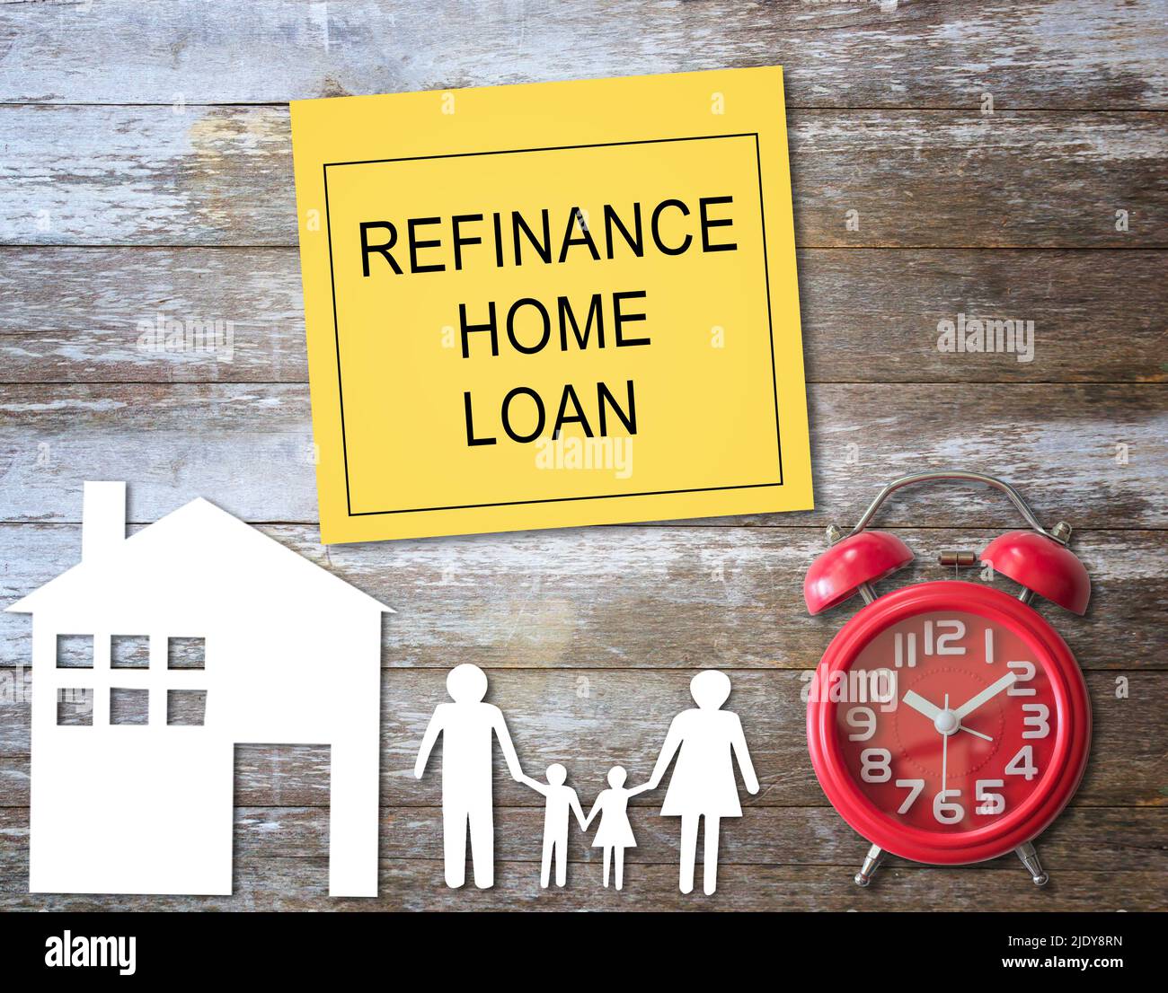 Text mit Refinanzierung Home Loan Schreiben Sie auf eine gelbe Haftnotiz und Home Family Papier und roten Wecker auf Holztisch Hintergrund. Hypothekenkonzept. Stockfoto