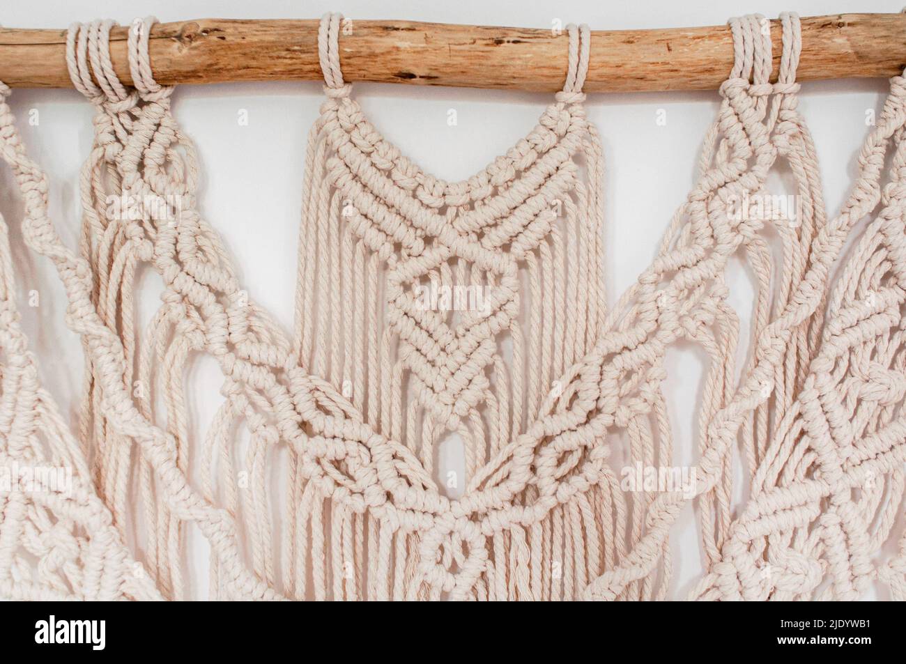 Ein Teil des Dekors im Stil der Weberei Macrame handgefertigt aus beigen natürlichen Fäden auf einem weißen Hintergrund Stockfoto