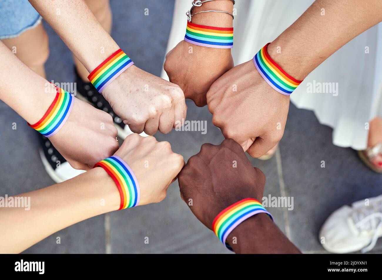 Gruppe von Menschen mit mehreren Rassen, die sich die Hände mit Armbändern mit LGBT-Regenbogenflagge zusammenlegen. Konzept für Vielfalt, Stolz, Gleichheit und Einheit. Stockfoto