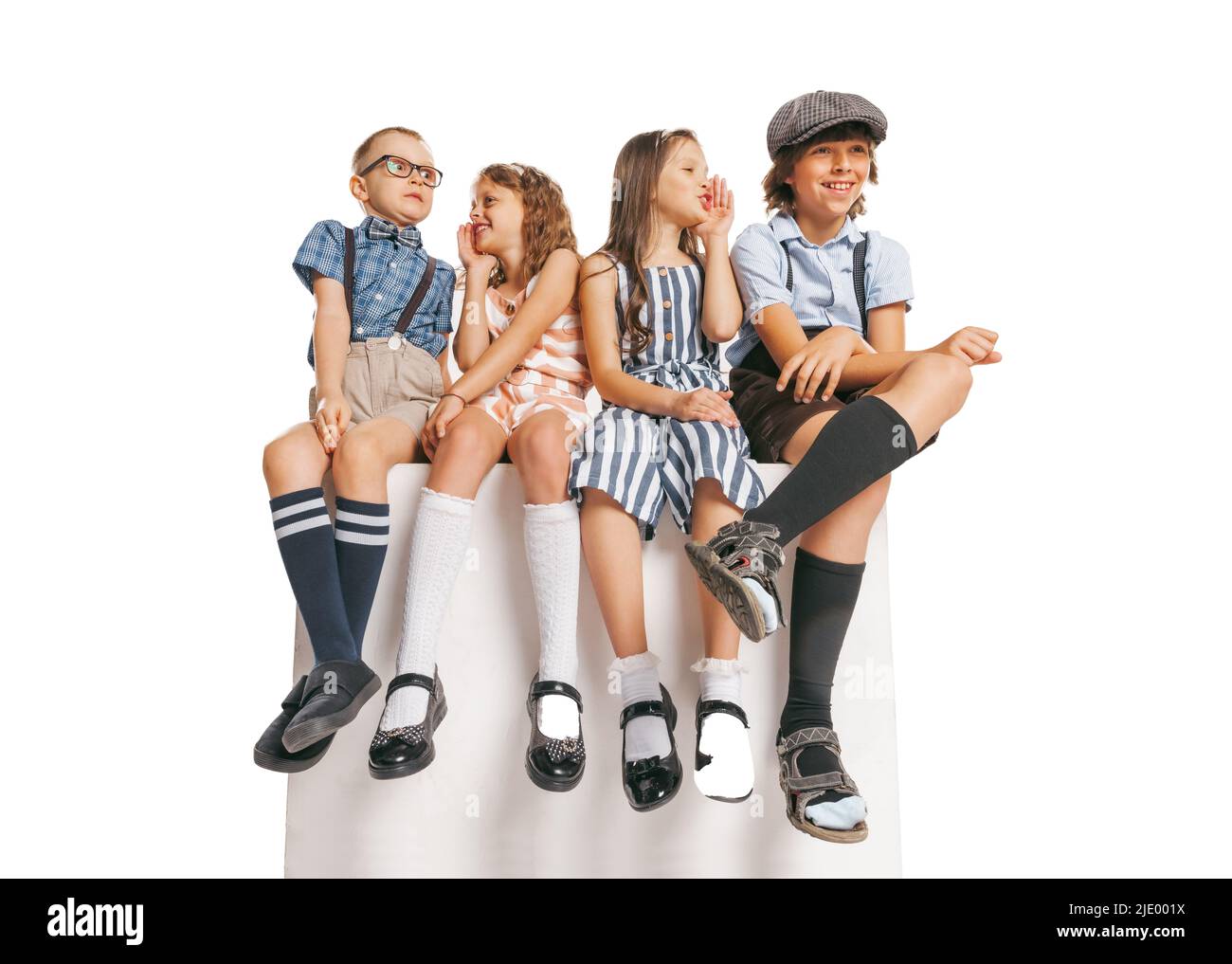 Gruppe von emotionalen Kindern im Retro-Stil Sommer-Outfit sitzen zusammen isoliert auf weißem Hintergrund. Konzept von Kunst, Freundschaft, Hoffnung, Jugend, Mode Stockfoto