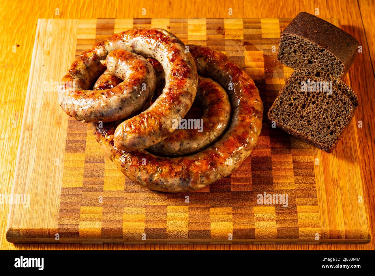 Gegrillte Würstchen auf einem Schneidebrett mit Brot. Stockfoto