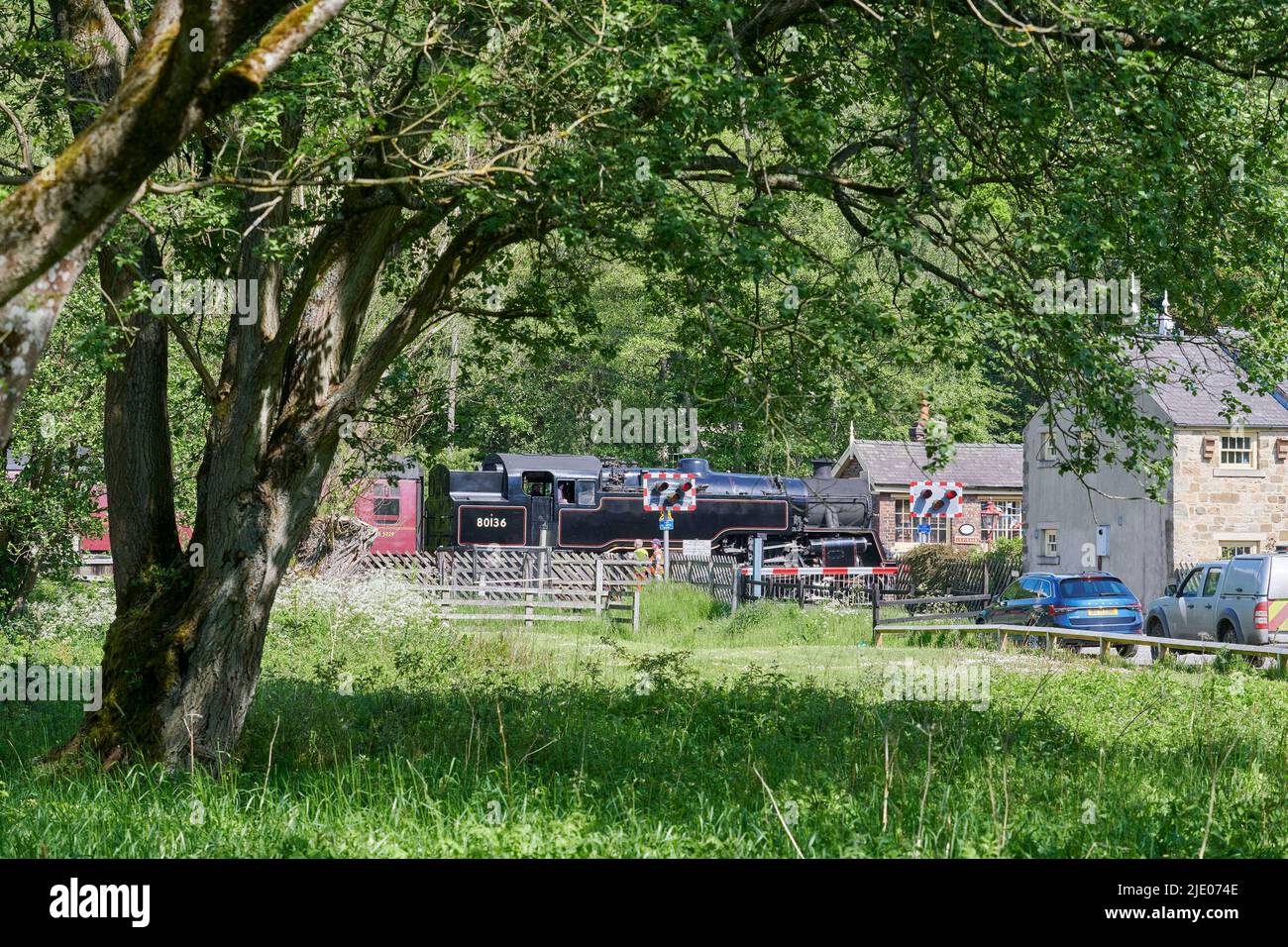 Dampfzug, der den Verkehr auf der North Yorks Moors Railway am Bahnübergang Levisham, North Yorkshire Moors National Park, Nordengland, Großbritannien, hält Stockfoto