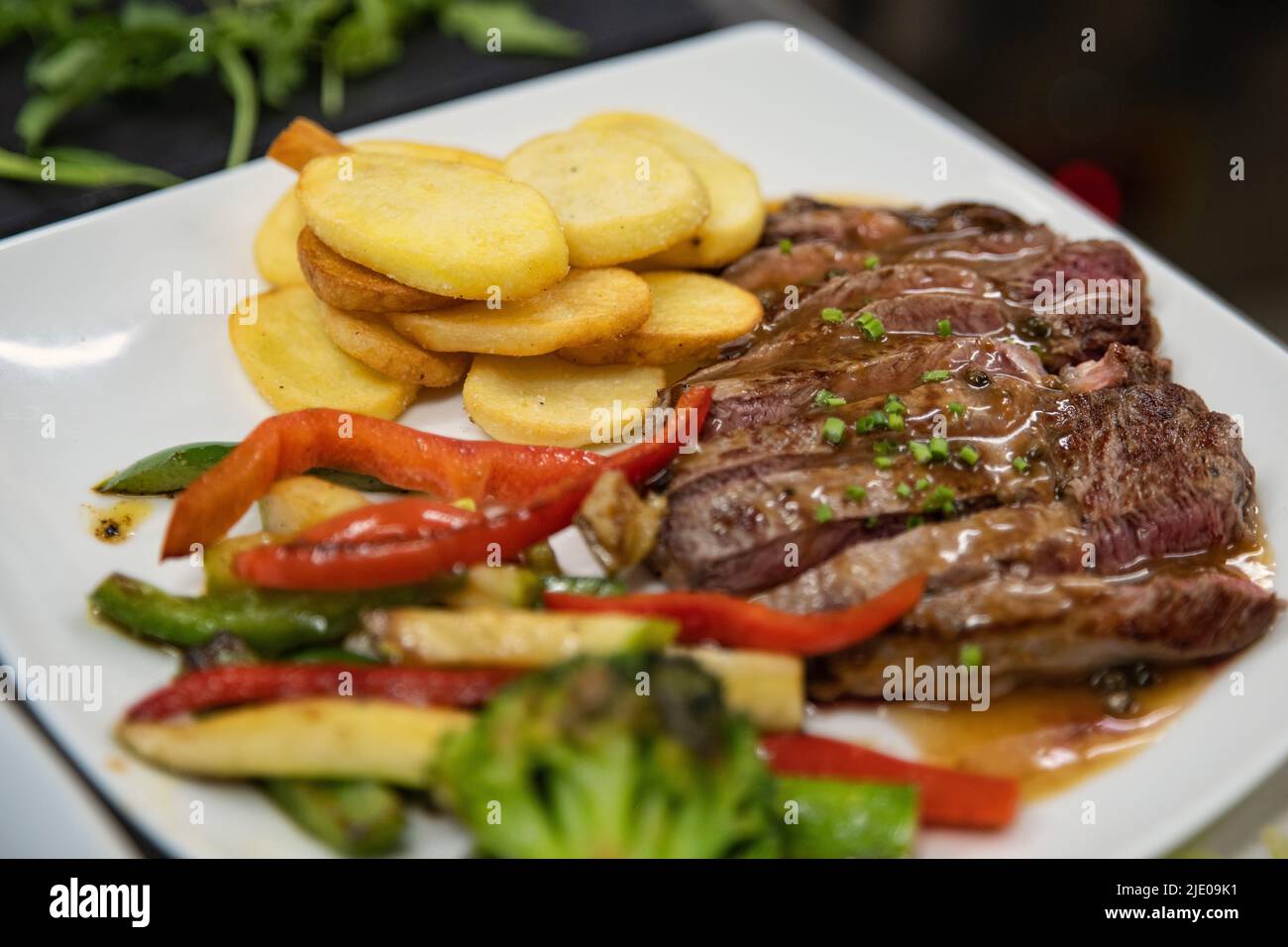 Köstliche Mahlzeit mit Pfahlstreifen, Kartoffelchips und gegrilltem Gemüse auf einem weißen Teller, leckeres Gericht mit mehreren Lebensmittelgruppen ein Nährstoffkraftwerk Stockfoto
