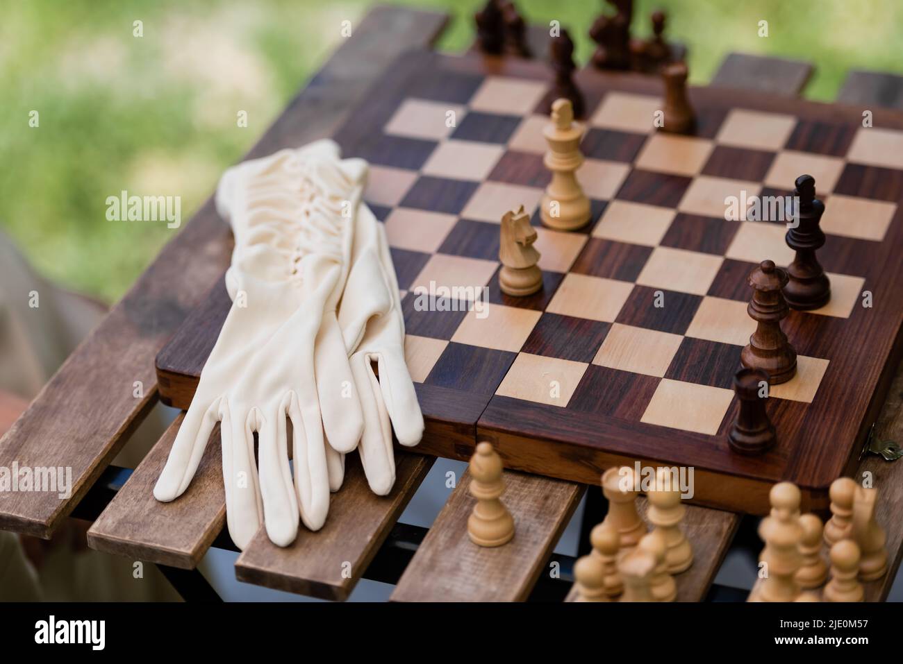 Handschuhe in der Nähe von Holzfiguren auf dem Schachbrett im Park Stockfoto