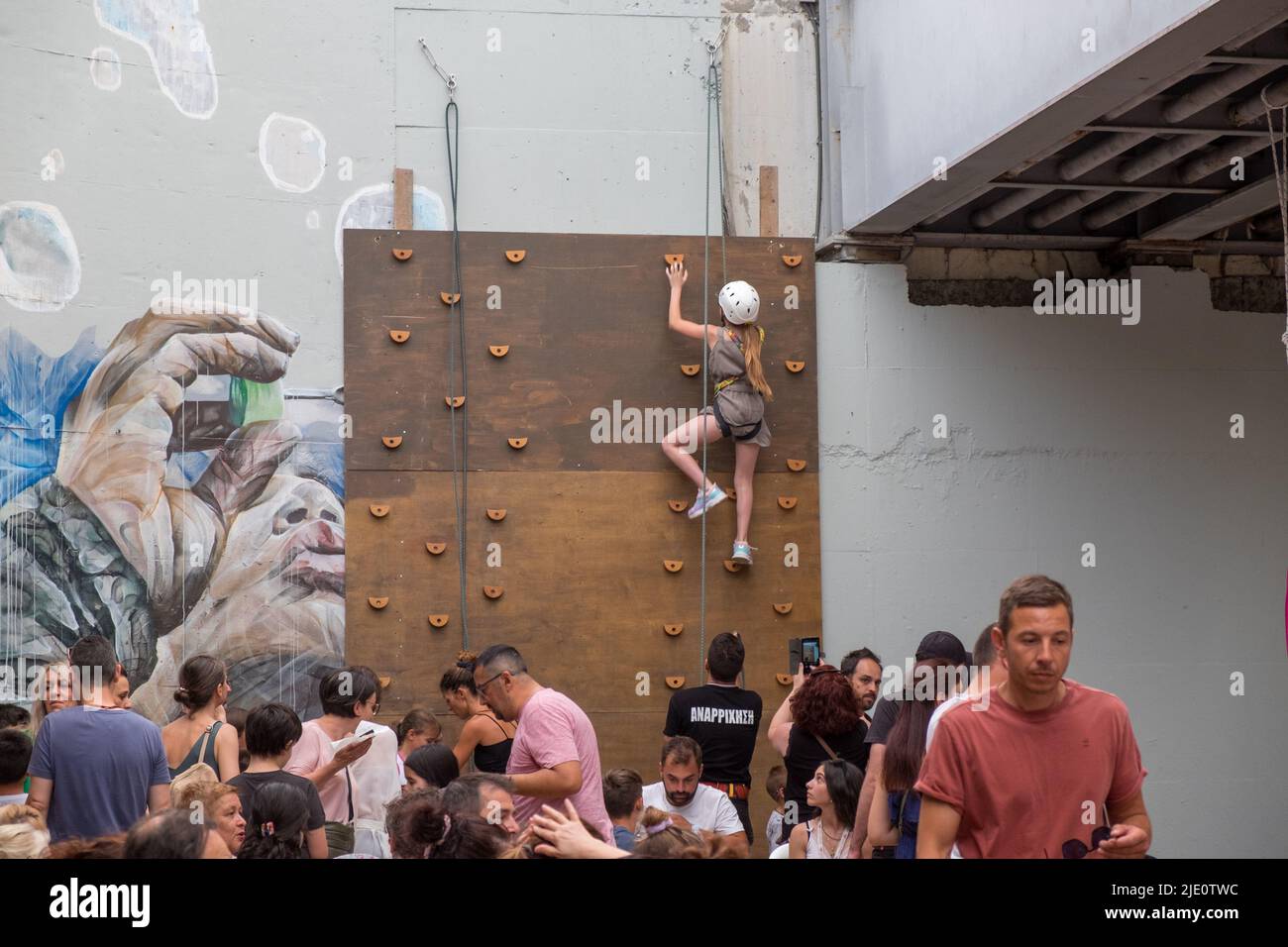 Junges Mädchen, das während einer Veranstaltung eine mit einem Seil getiterte Wand kletterte Stockfoto