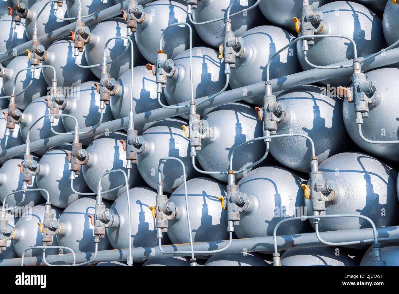 Viele verschiedene kleine Metallflaschen, die mit Gas oder Benzin gefüllt sind, werden in großen Stapeln gestapelt und von der hellen, warmen Tagessonne beleuchtet Stockfoto