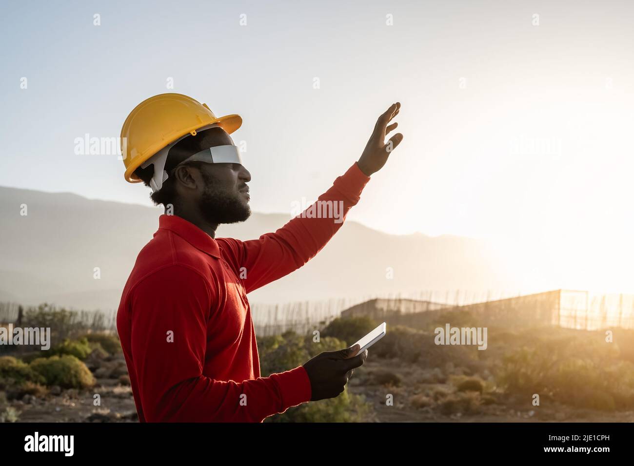 Afrikanischer Ingenieur, der mit futuristischen Gläsern auf der Baustelle arbeitet - Technologie und Zukunftskonzept der Industrie Stockfoto