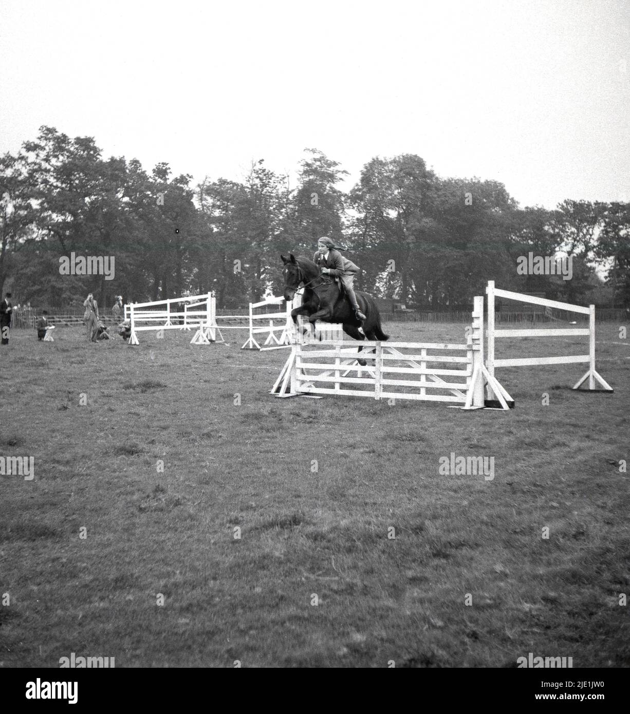 1940s, historisch, ein junges Mädchen, das auf einem Pferd reitet und einen Zaun auf einem Feld springt, ohne Helm, Bramhall, Stockport, England, VEREINIGTES KÖNIGREICH. Stockfoto