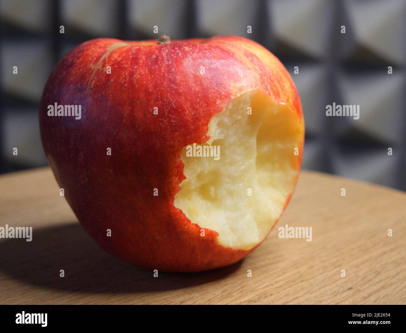 Ein gebissenen roten Apfel auf einer hölzernen Oberfläche. Reife Äpfel aus nächster Nähe. Stockfoto