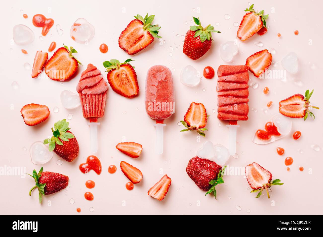 Eiszapfen und frische Erdbeeren auf rosa Hintergrund. Stockfoto