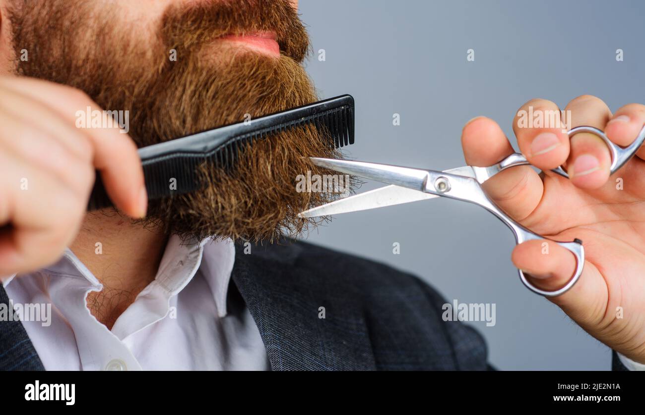 Barbershop. Bärtiger Mann mit Schere und Kamm. Friseurwerkzeuge. Professionelle Bartpflege. Salon für Männer. Stockfoto