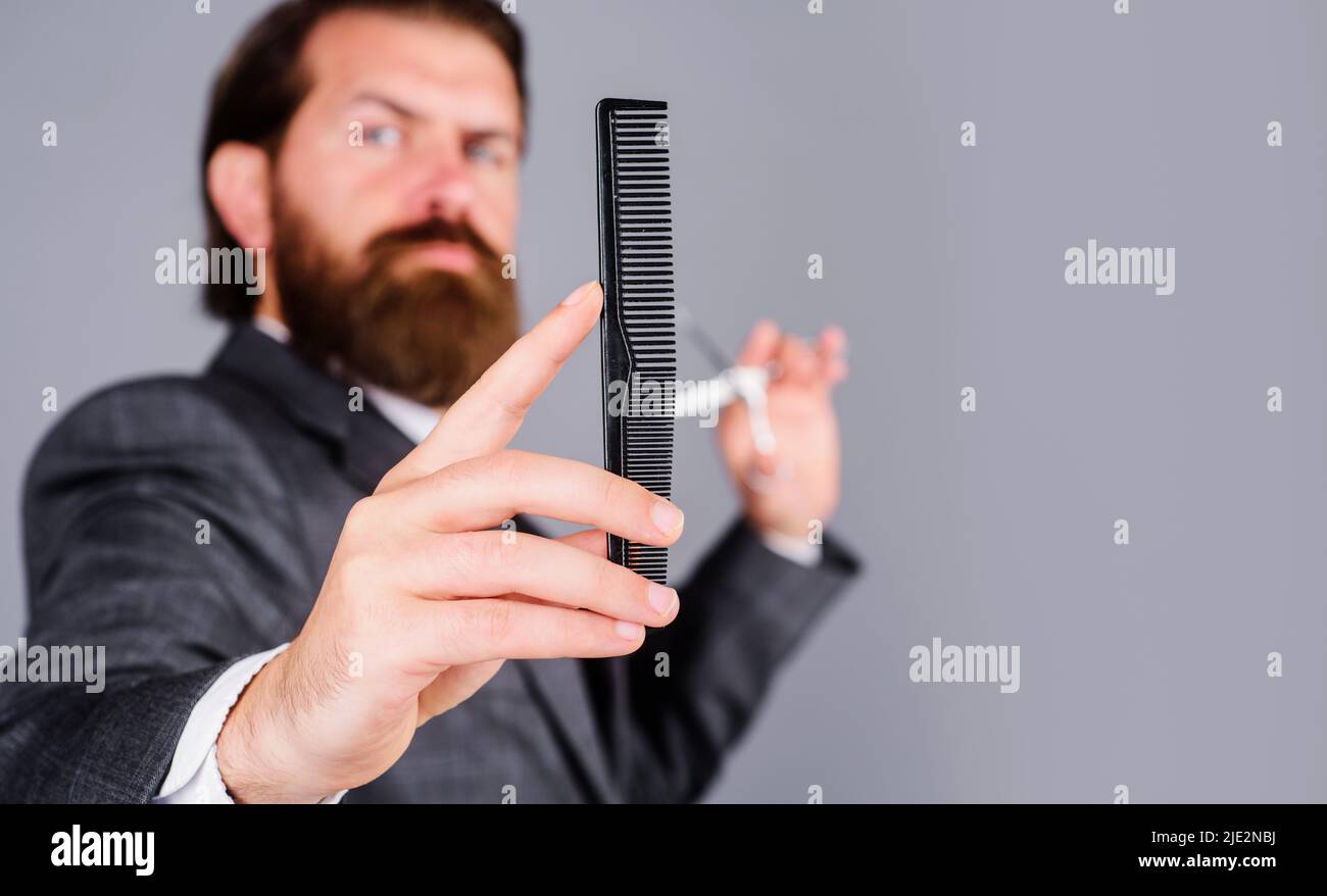 Barbershop-Werbung. Bärtiger Mann mit Frisierkamm. Zubehör für Haarschnitt. Salon für Männer. Stockfoto