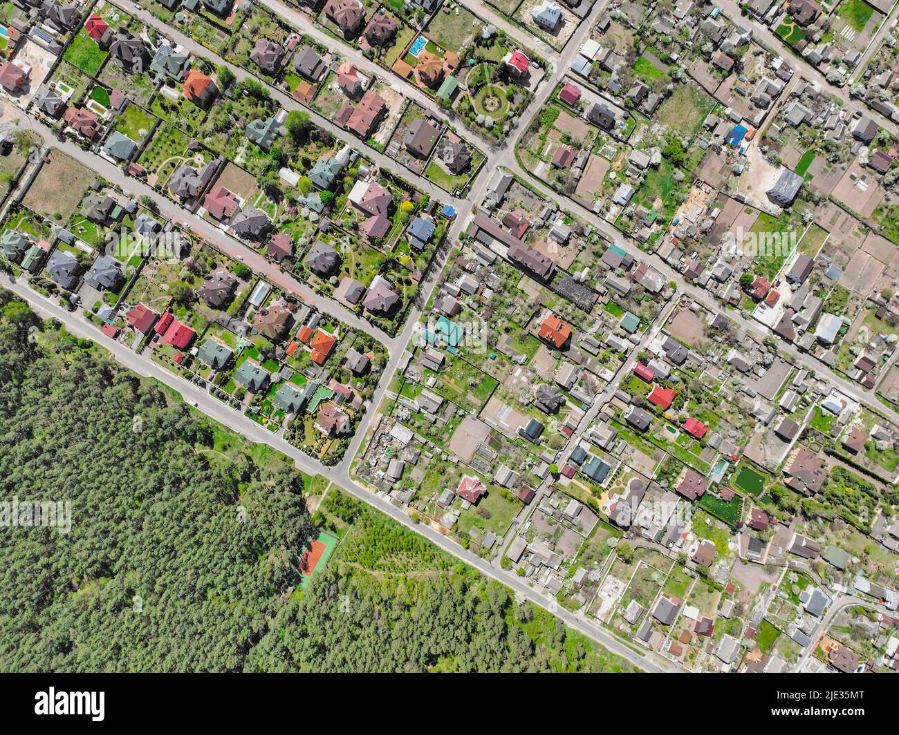 Wohnhäuser mit Ziegeldächern in der Nähe der Stadt. Vorort in der Nähe eines Waldes. Cottages in Wohngebieten mit geringer Gebäudedichte - Luftdrohne Blick auf das Dach. Stockfoto