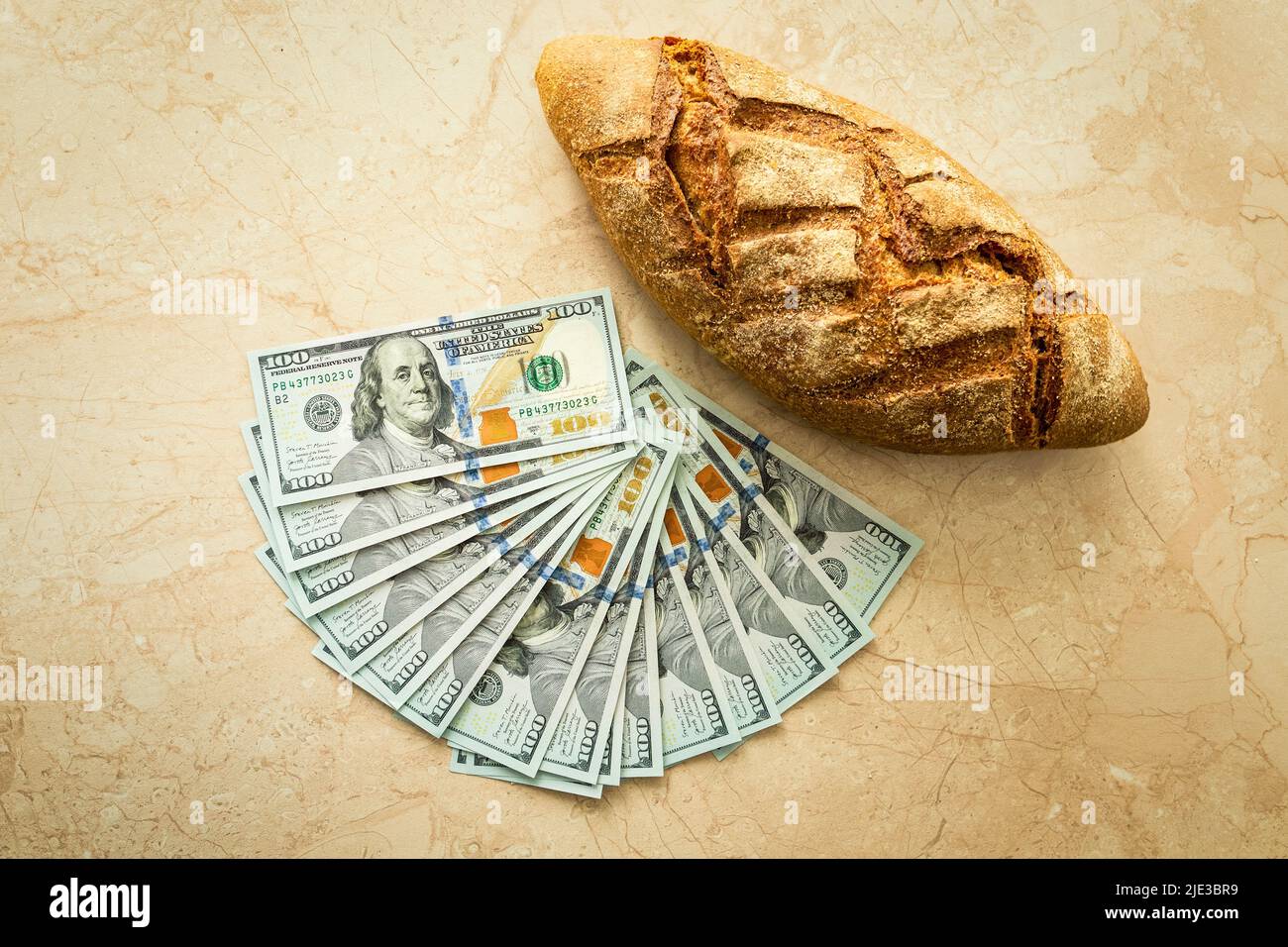 Brot und 100-Dollar-Banknoten. Wohlstand, Erfolg, Wohlstand, globale Nahrungsmittelkrise. Stockfoto