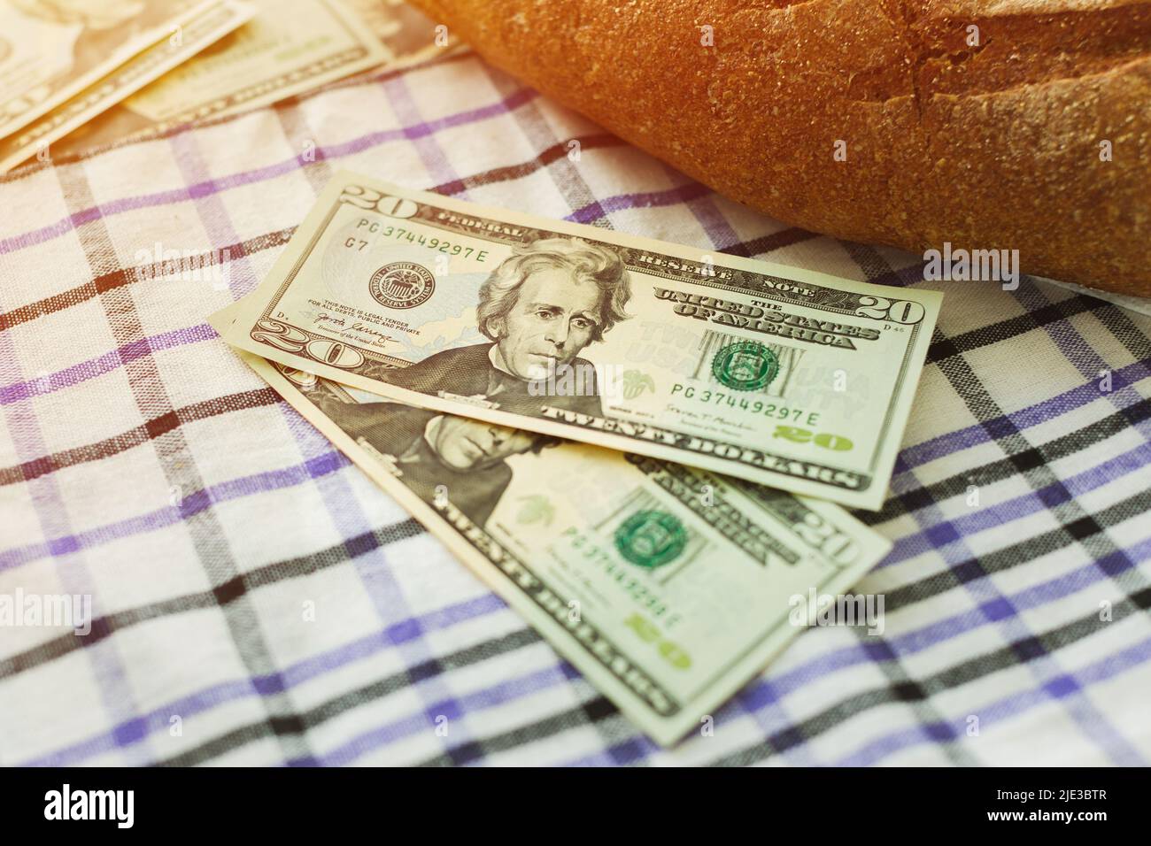 Zwei 20-Dollar-Scheine neben frischem Brot auf dem Tisch. Konzept für die Nahrungsmittelkrise der Welt. Stockfoto
