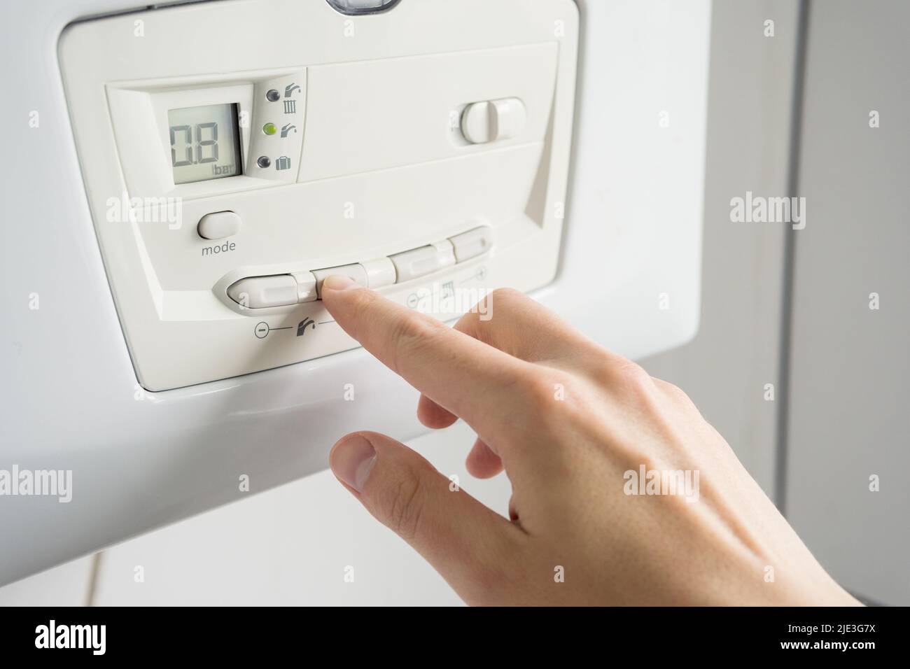 Mann, der die Temperatur auf einer Heizkesselkonstruktion einlegt. Stockfoto