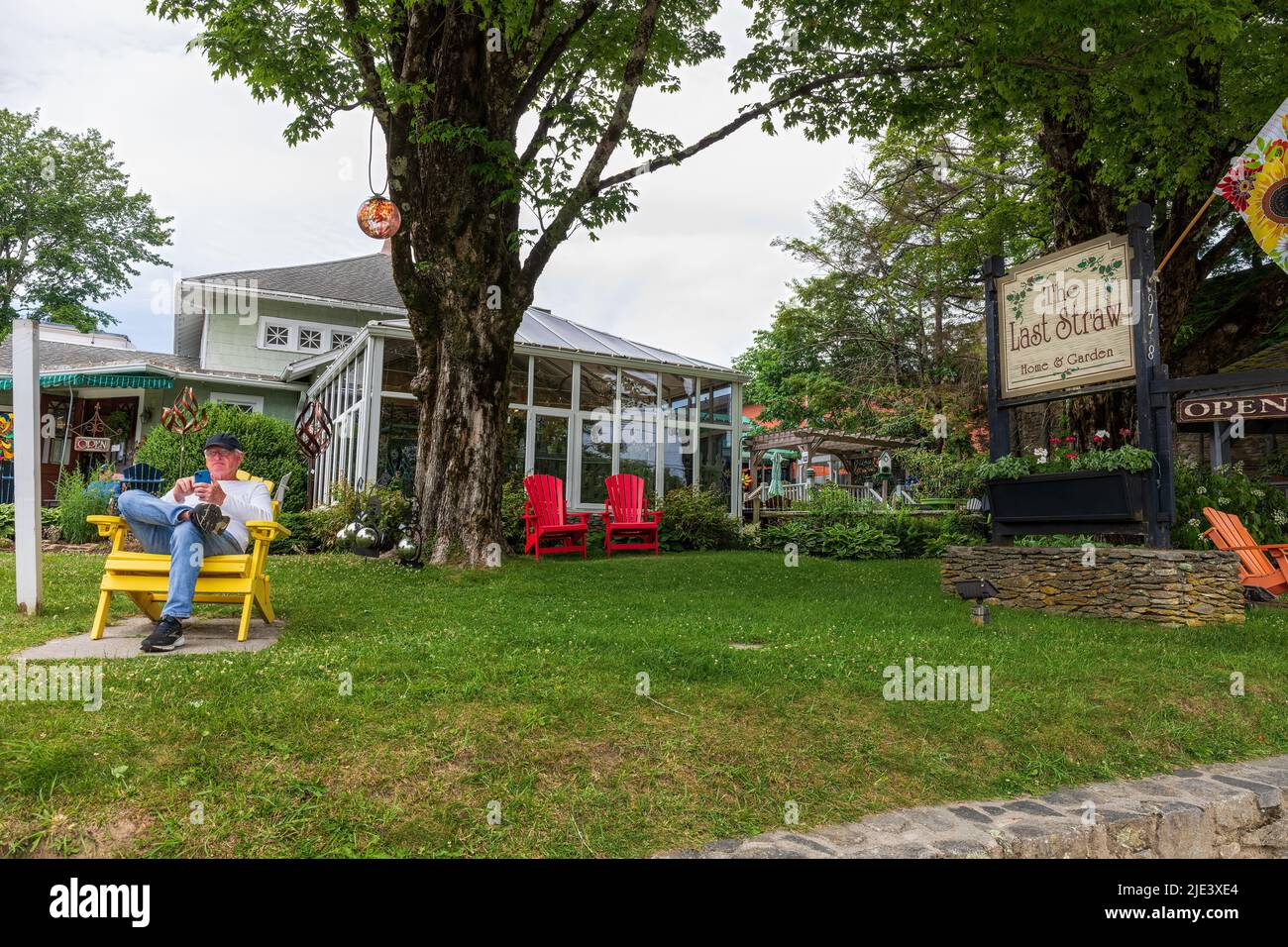 BLOWING ROCK, NC, USA-20 JUNE 2022: The Last Straw Shop auf der Main Street, zeigt Gebäude, Schild und einen Mann im Stuhl, der Handy liest. Stockfoto