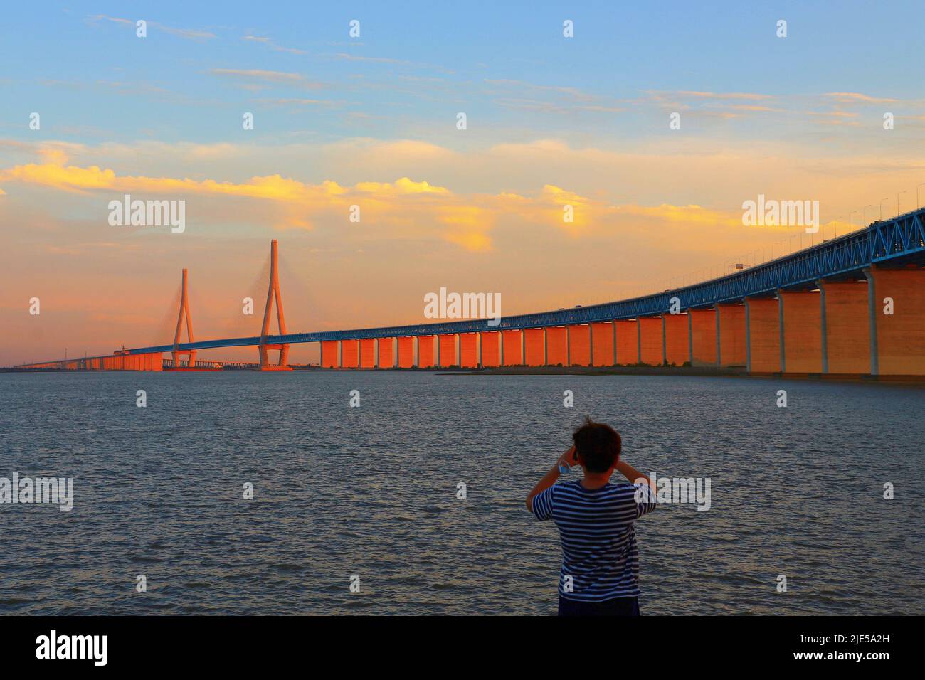 NANTONG, CHINA - 24. JUNI 2022 - die untergehende Sonne scheint auf den Pfeilern der Eisenbahnautobahn-Brücke des Flusses Shanghai-Suzhou-Nantong Yangtze in Nantong, Osten Stockfoto