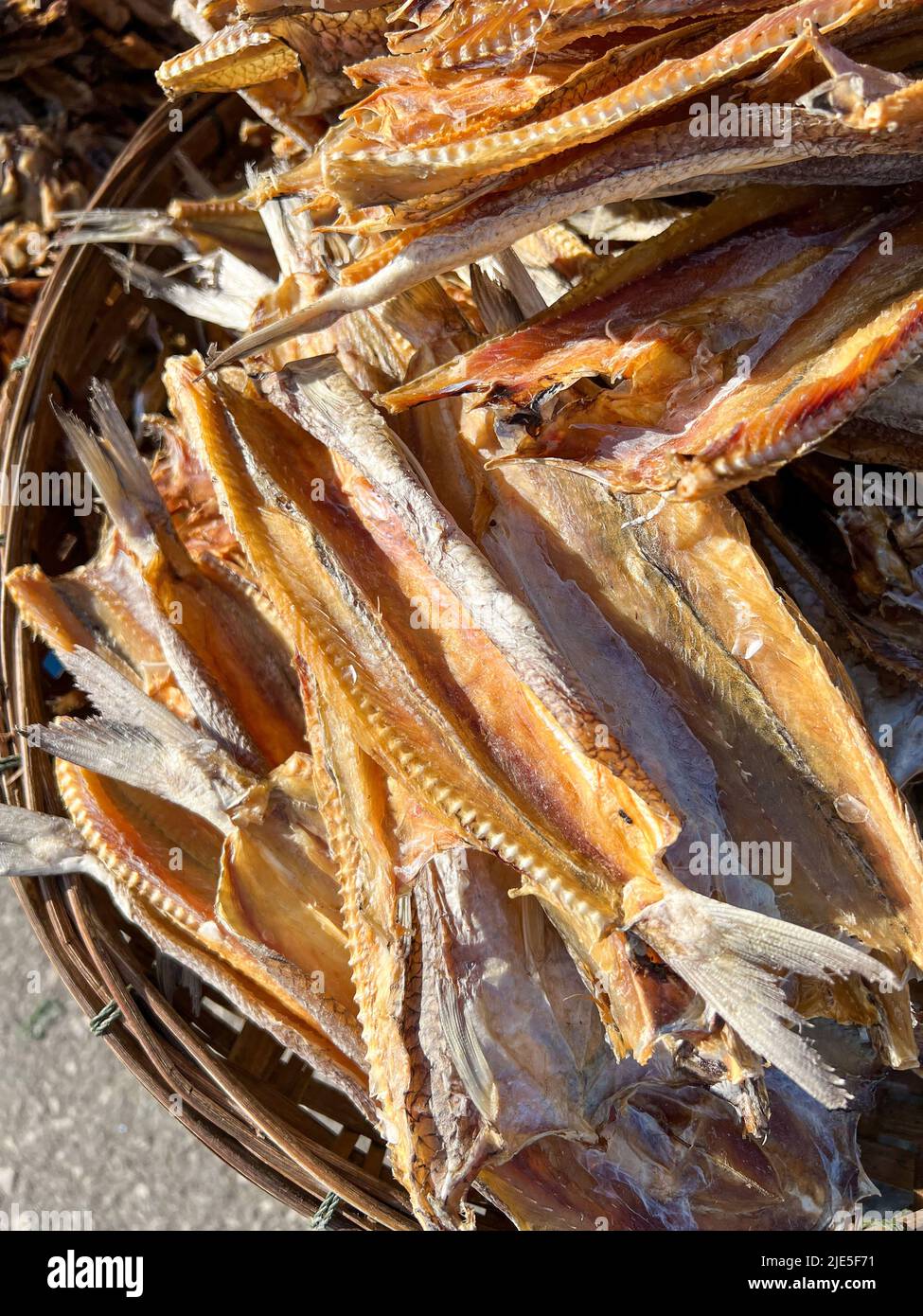 Getrocknete Meeresfrüchte wie getrockneter Fisch im Bambuskorb trocknen unter Sonnenlicht auf dem Markt aus Stockfoto