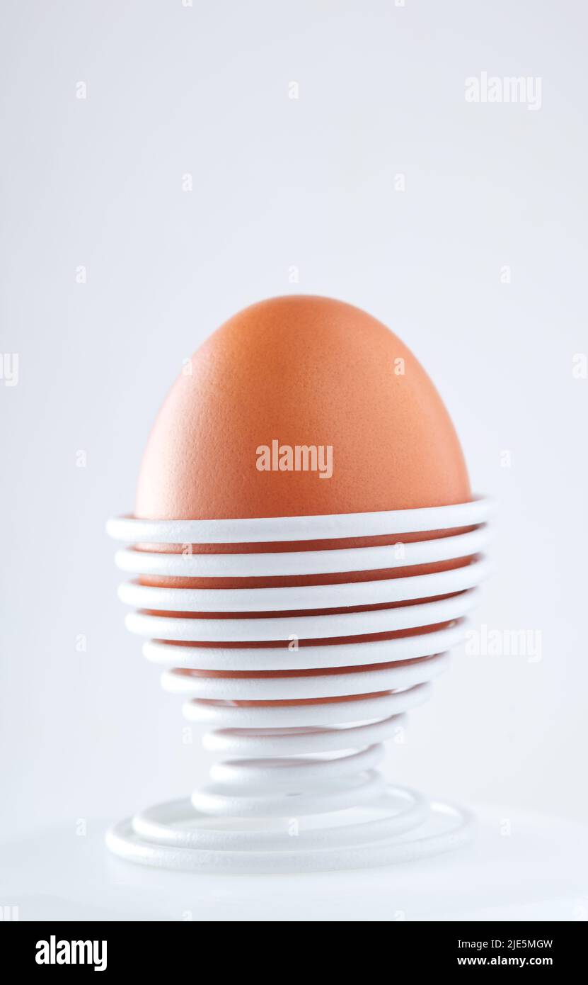 Ein gekochtes Ei in einer spiralförmigen Metallstütze, isoliert auf weißem Hintergrund Stockfoto