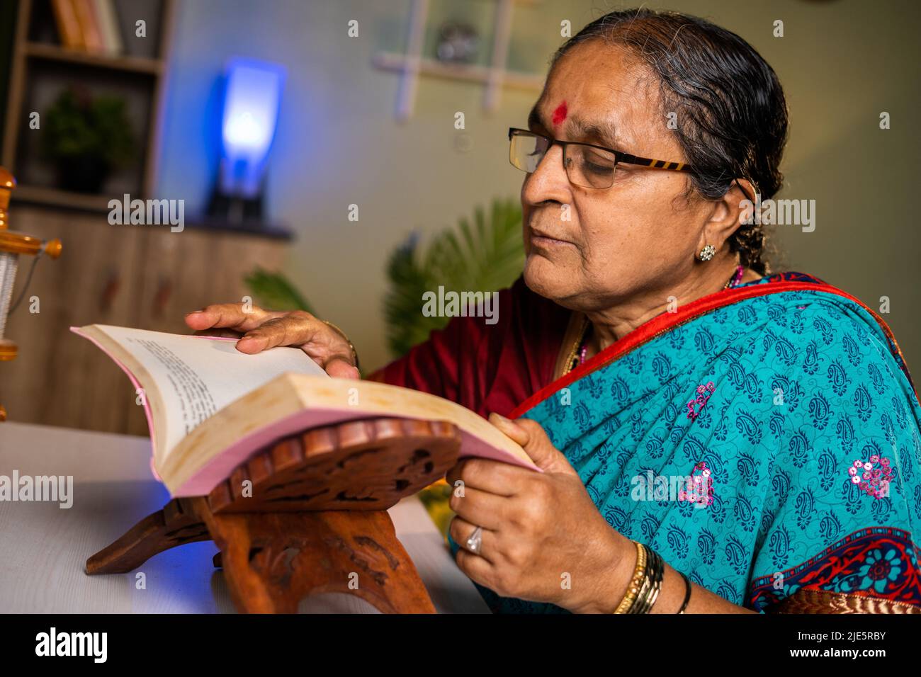 Ältere indische Frau mit Brille, die zu Hause Buch liest - Konzept der Freizeitbeschäftigung, Hobbys und Wissen. Stockfoto
