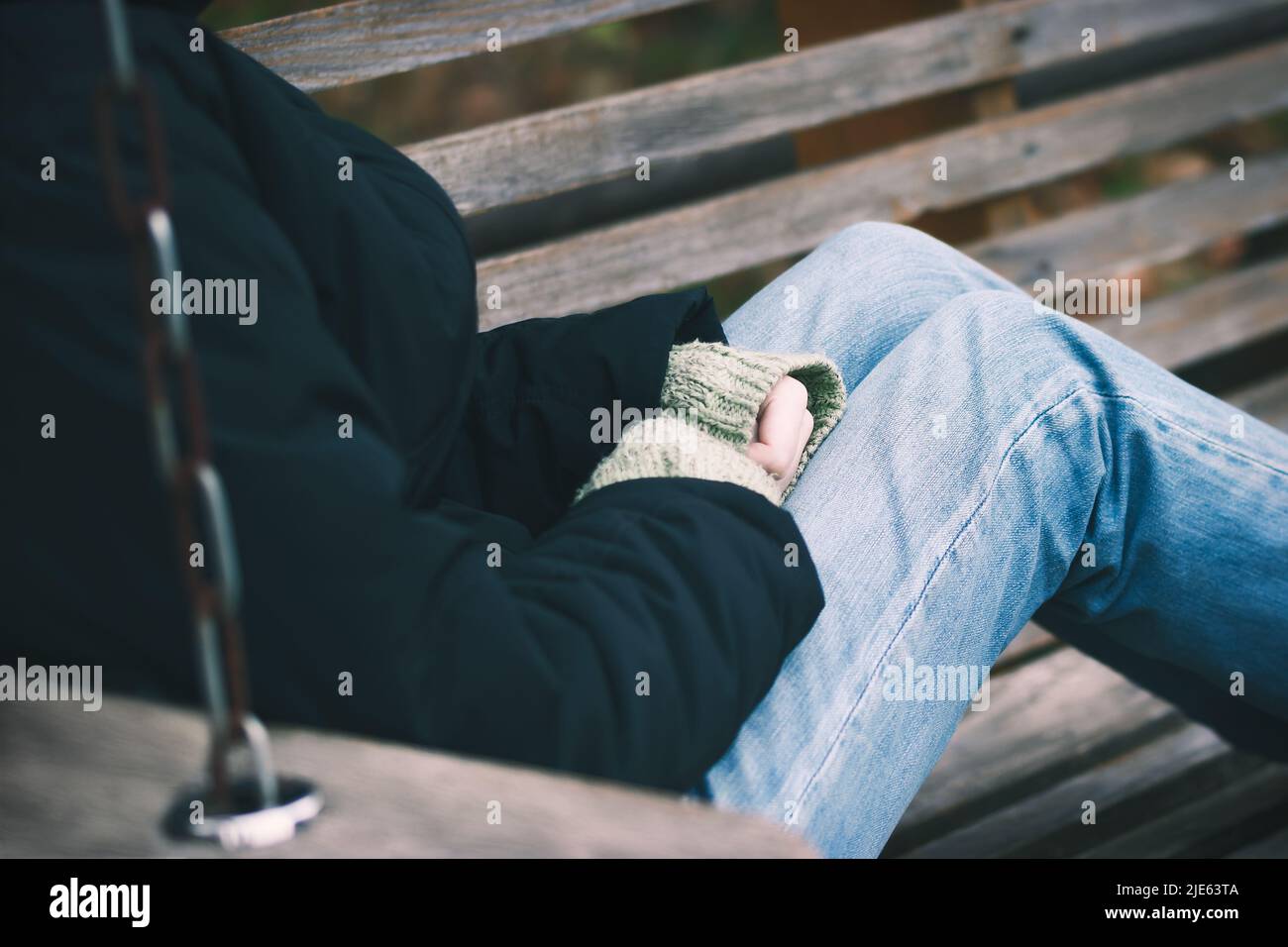 Einsames Mädchen, das auf einer Bank im Herbstpark sitzt. Stockfoto
