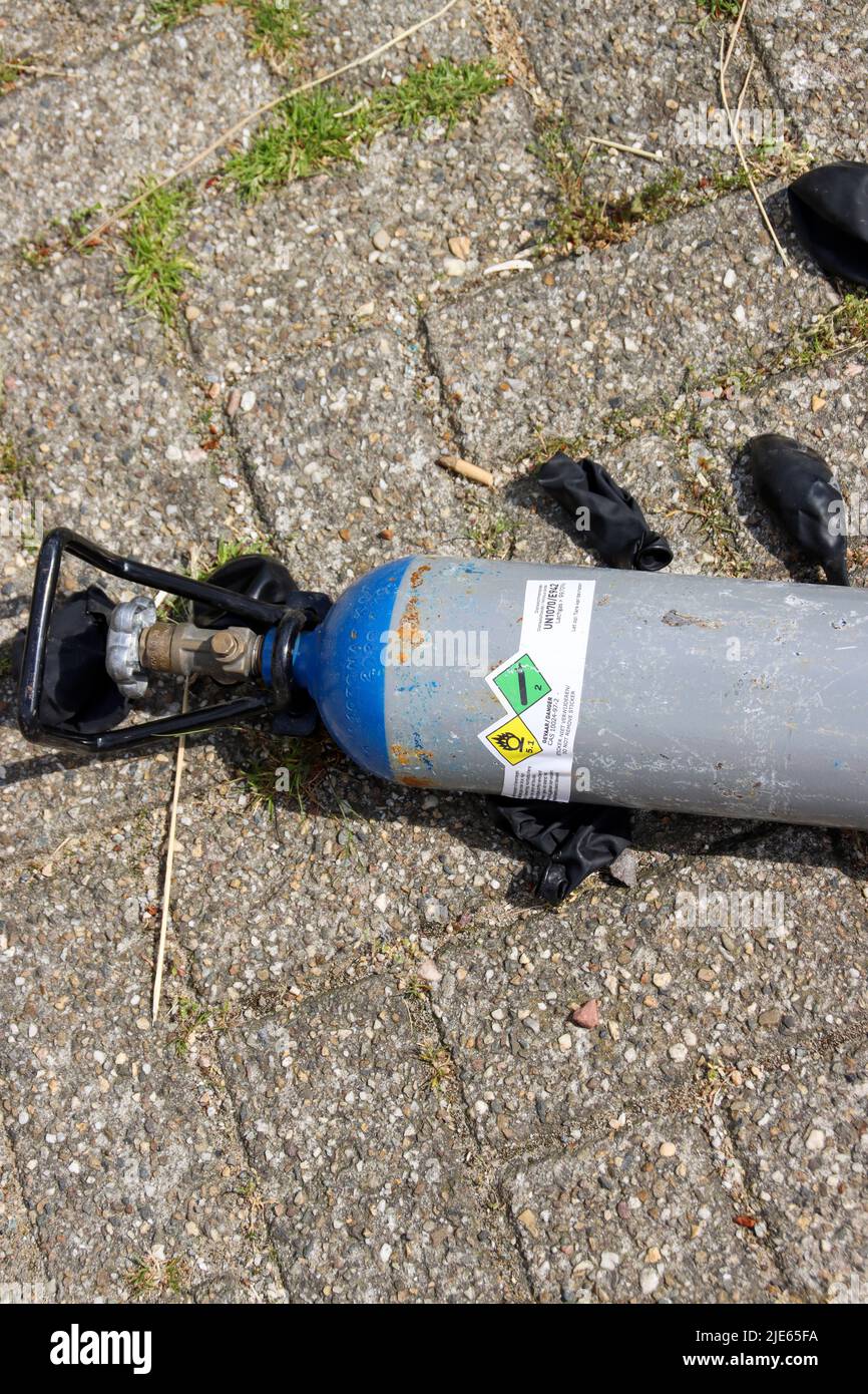 Gasflaschen mit Lachgas und schwarzen Ballons wurden nach der Einnahme als Drogen in Den Haag auf dem Parkplatz gelassen Stockfoto