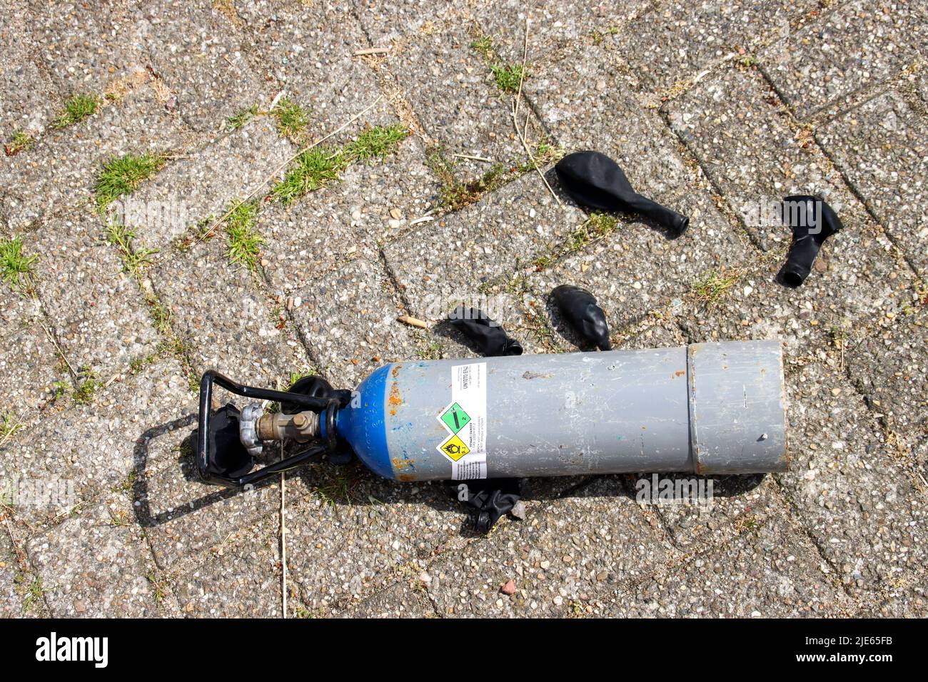 Gasflaschen mit Lachgas und schwarzen Ballons wurden nach der Einnahme als Drogen in Den Haag auf dem Parkplatz gelassen Stockfoto