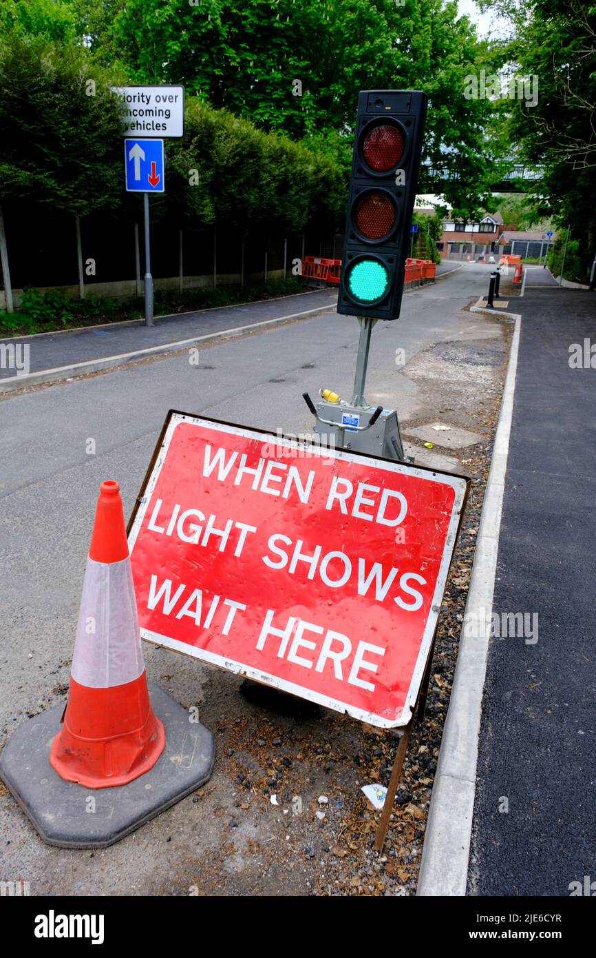 Rotes Warnschild auf der britischen Straße „Wenn die rote Ampel hier warten anzeigt“ neben der vorübergehenden Ampel Stockfoto