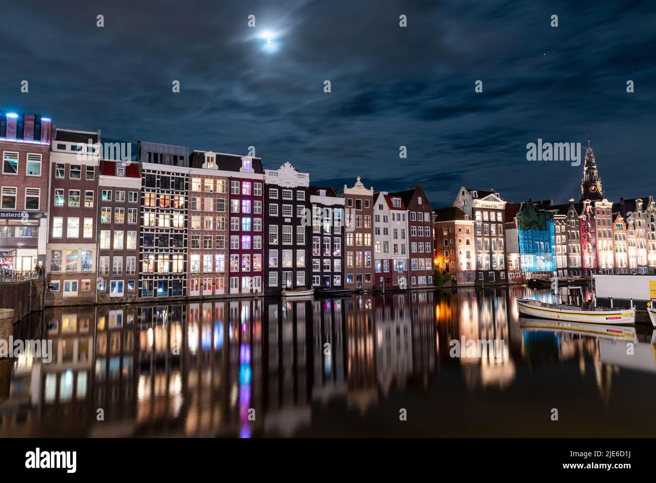 Nachtblick auf Amsterdam mit beleuchteten Kanalhäusern und Reflexionen auf dem Wasser. Das Bild fängt die historische Architektur und das friedliche A der Stadt ein Stockfoto