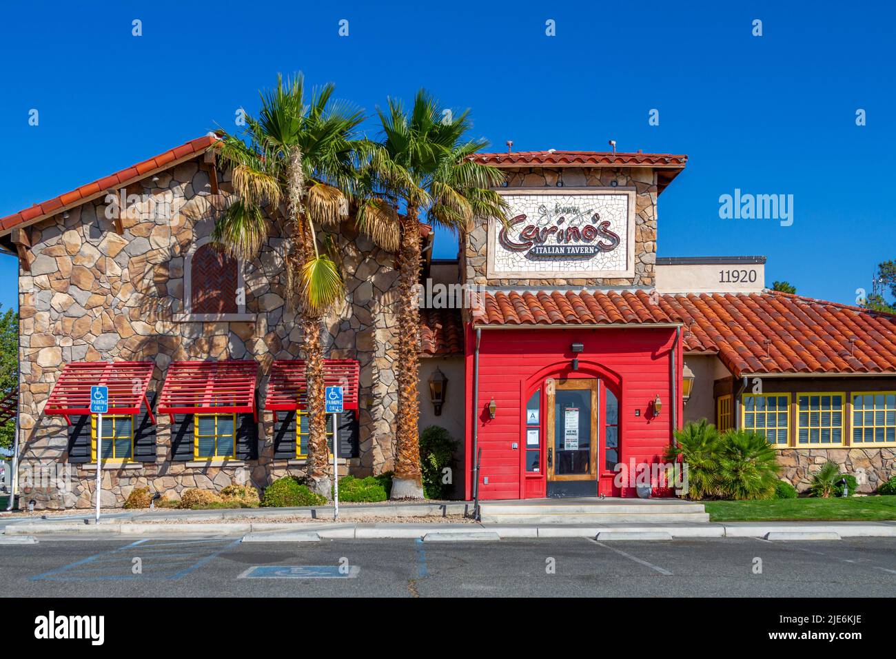 Victorville, CA, USA – 23. Juni 2022: Gebäude außerhalb des italienischen Restaurants von Johnny Carino mit grünem Gras und Palmen in Victorville, Kalifornien Stockfoto