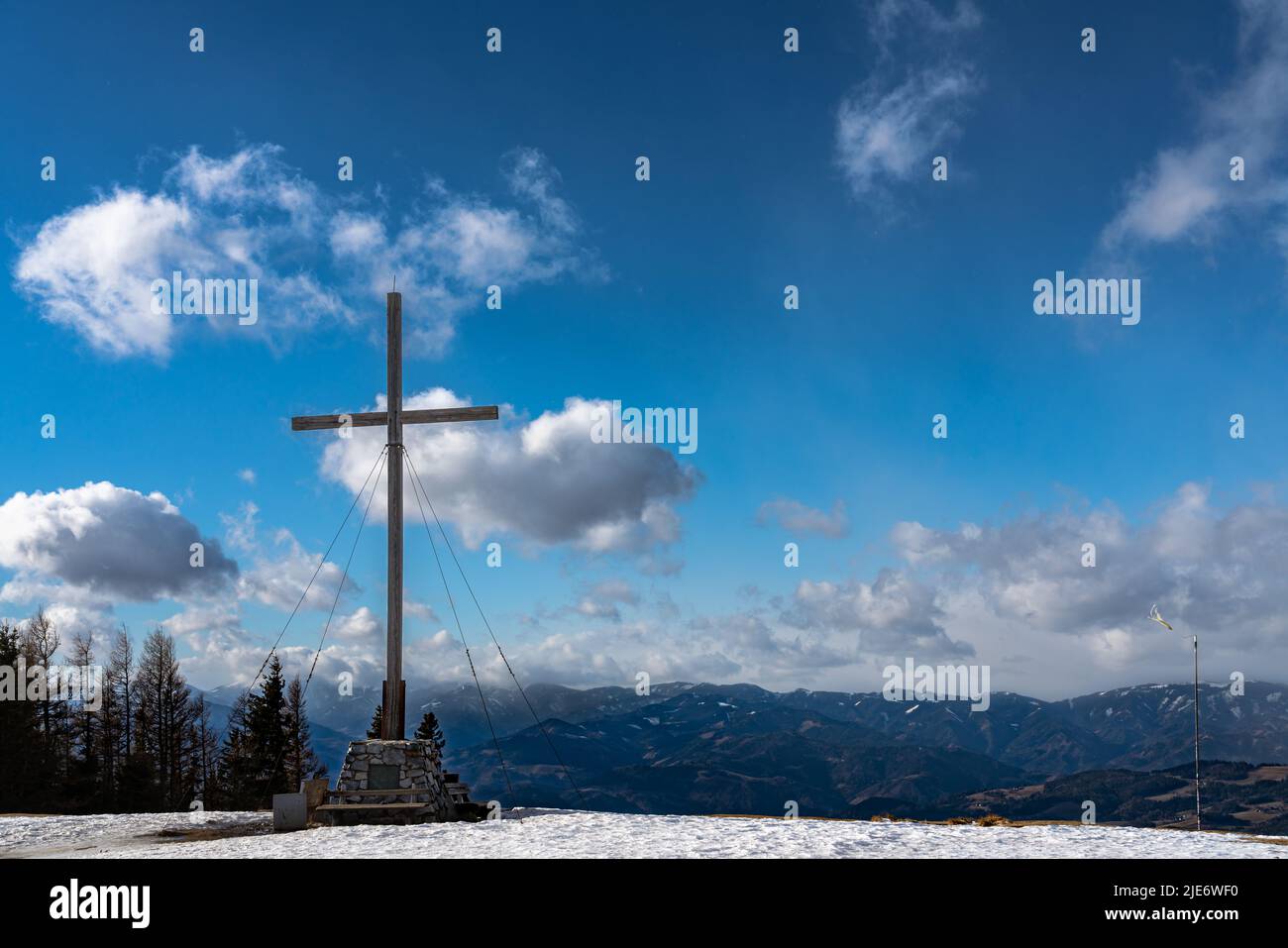 Panorama-Luftaufnahme der Alpen im Süden der Steiermark vom Gipfel des Schöckl bei Graz mit Gipfelkreuz und blauer Himmelswolke am sonnigen Wintertag, Sankt Rad Stockfoto