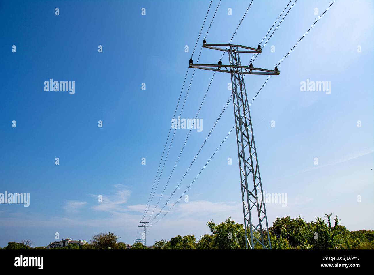 Elektrische Unterstützung von Hochspannungskabeln. Metallmast mit Hochspannungskabeln und Glasisolatoren gegen klaren blauen Himmel. Stockfoto