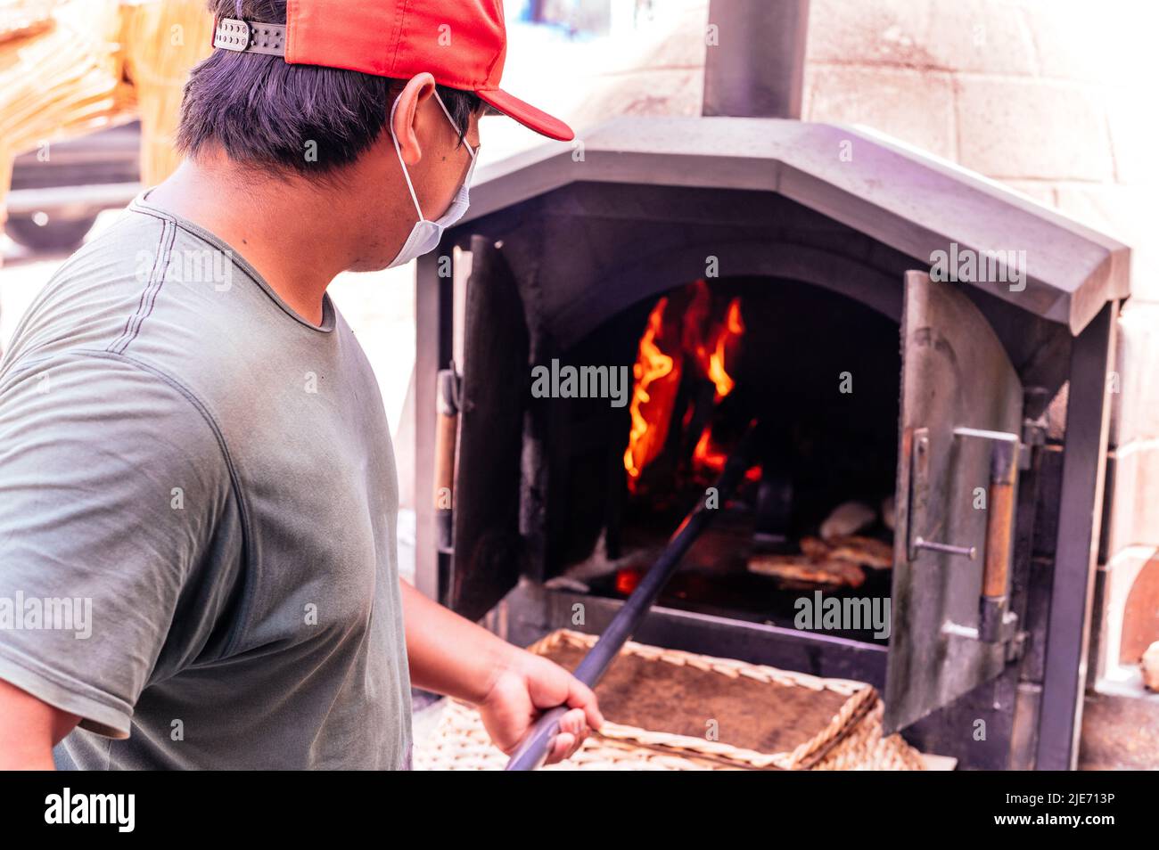 Baker backen Brot in einem Lehmofen Stockfoto