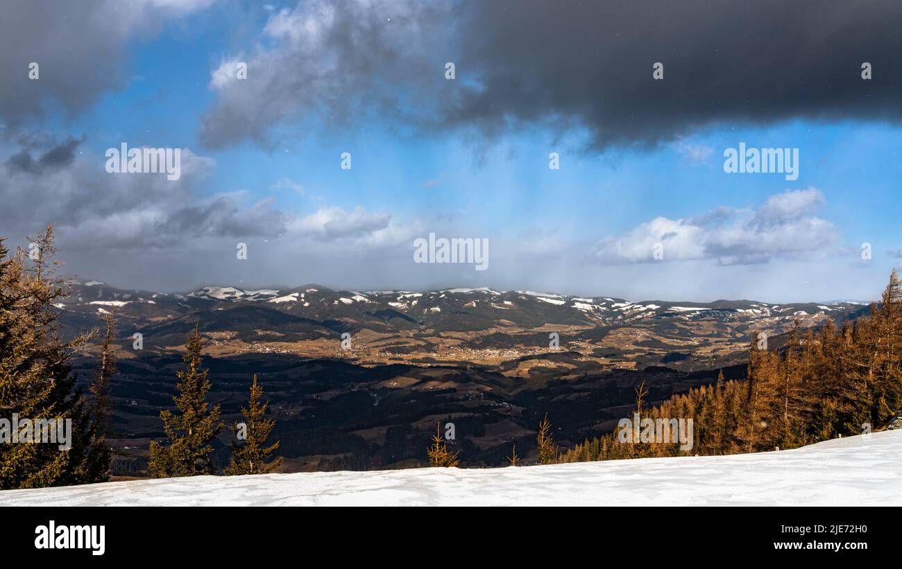 Panorama-Luftaufnahme der Alpen im Süden der Steiermark vom Gipfel des Schöckl bei Graz mit blauer Himmelswolke am sonnigen Wintertag, Sankt Radegund, Österreich Stockfoto