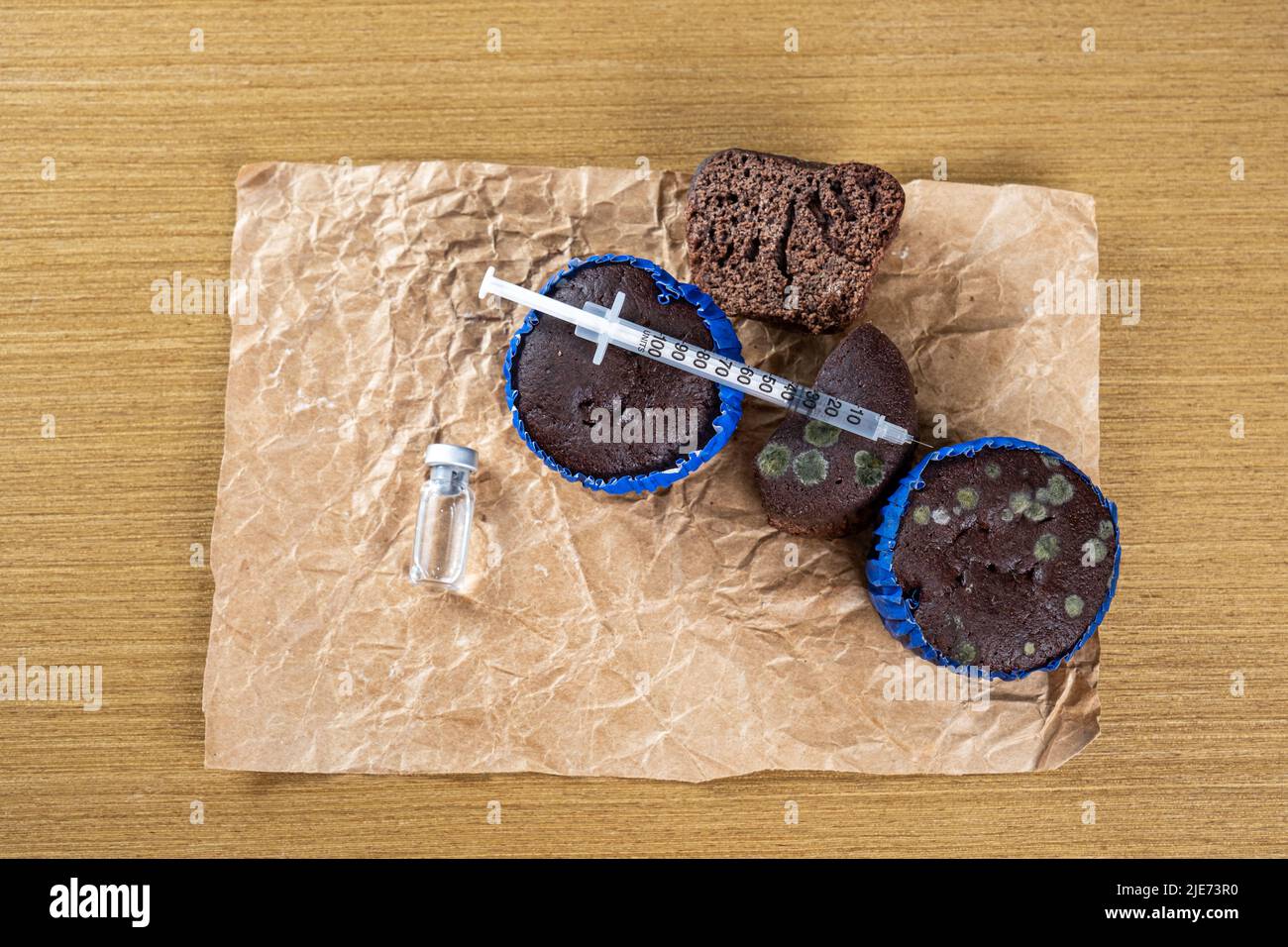 Spritze mit Insulin über mehrere verschimmelte Muffins top view. Stockfoto