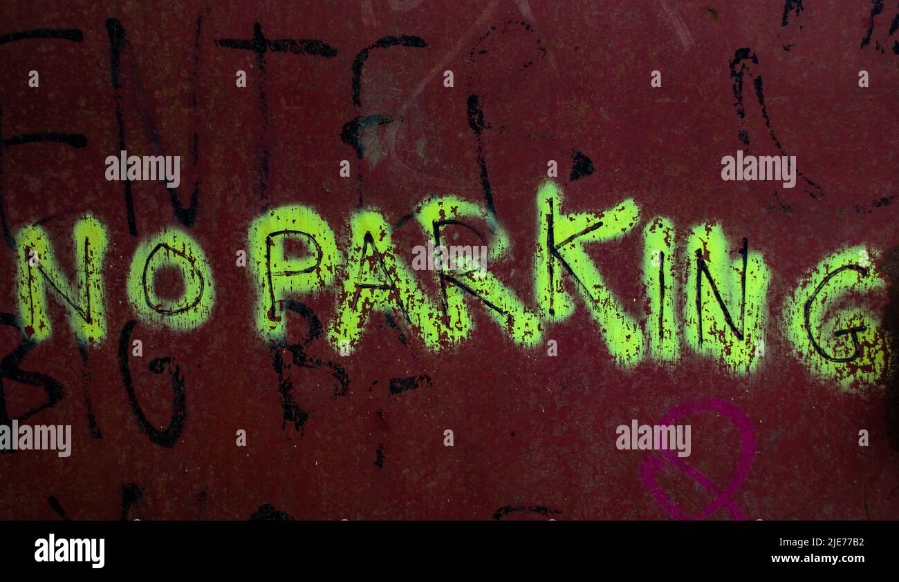 Auf einem Schild mit der deutlichen Aufschrift „KEIN PARKEN“ in einem Graffiti-Stil auf einer rostigen Metalltür. Stockfoto