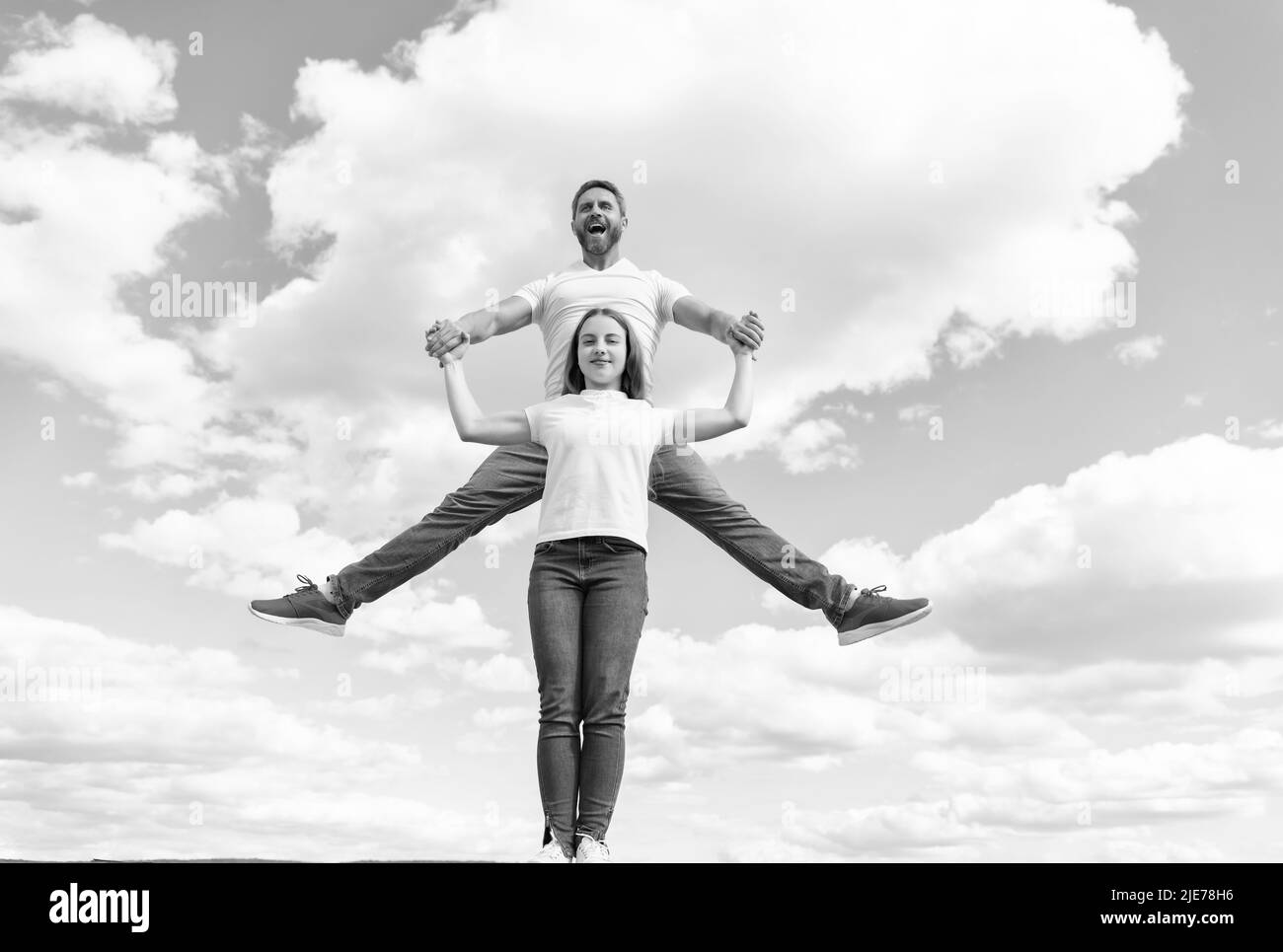 Glücklicher Vater und Tochter springen in den Himmel Stockfoto